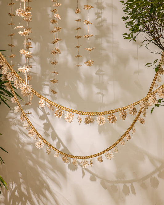 A handcrafted gold zari braid adorned with delicate origami flowers made from Rani Pink textile remnants. Perfect for draping across trees and festive spaces, adding an elegant, nostalgic charm to your celebrations.